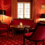 Eleganter roter Salon im Hotel Bad Eptingen mit Sitzgelegenheiten und klassischem Stil