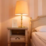Detailaufnahme eines Doppelzimmers im Hotel Bad Eptingen mit klassischem Nachttisch, Lampe und gemütlichem Bet